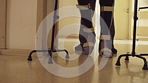 Legs of invalid in orthosis walking with support of two walking cane