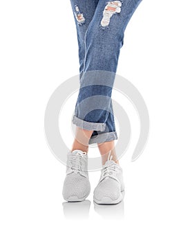 Legs in jeans and white sneakers isolated on a white background.