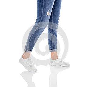 Legs in jeans and white sneakers isolated on a white background.