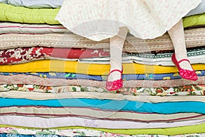 Legs of a little girl sitting on a pile of colorful mattresses. Decorations for the fairy tale The princess on a Pea