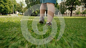Legs of a little girl walking on bright green grass in sneakers. Summer holidays