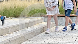 Legs of little schoolchildren walking through the school yard. All children are wearing sneakers.