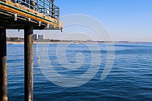 The legs of a long wooden pier in vast blue ocean water at Santa Monica Beach in Santa Monica