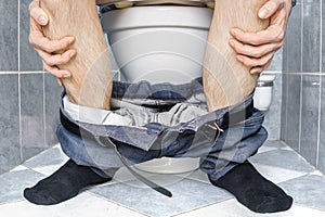 Legs of man with diarrhea who is sitting on toilet photo