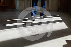 Legs of a man in an expensive suit and black shoes during a step. A person walks along the corridor of the living room or hotel ma