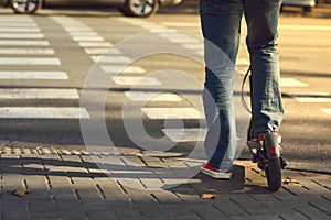 Beine aus mann Turnschuhe auf der elektrisch Roller auf der übergang auf der die stadt straßen 