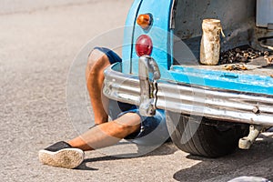 The legs of a man under the car, Vinales, Pinar del Rio, Cuba. Car repairs. Close-up.