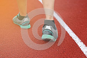 Legs of a man walk around the track on a sunny spring day