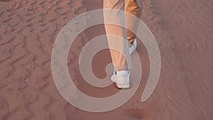 legs of man walking over sand,closeup, rear view, person lost in desert, lonely traveller strolling
