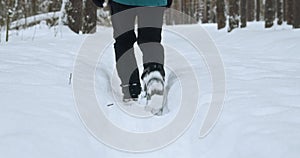 the legs of a man walking through a winter forest through deep snowdrifts