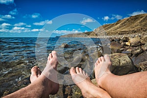 Legs of man and woman relaxing on a sea