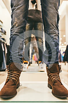 Legs of mannequins in the store dressed in blue jeans and brown leather shoes
