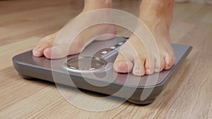 Legs of men or woman stepping on weighting scale for body measuring while losing weight