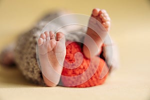 Legs of a newborn. Baby feet with a crochet heart. The tiny foot of a newborn in soft selective focus.