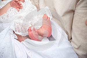 legs newborn baby girl in the parent hands on a white background clothes