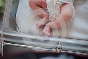 Legs of a newborn baby lying in a couveuse. The child has just been born and is in the hospital clinic with his mother. Natural photo