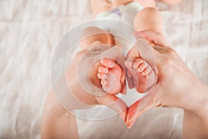 Legs of a newborn in hands closeup. Baby`s feet and copy space. Infant care and colic.