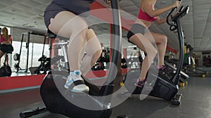 Legs of obese female pedalling slowly at exercise bike in the fitness club