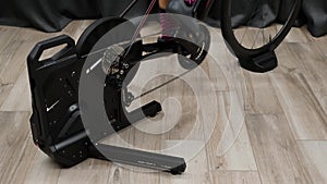 Legs pedaling on home smart trainer with powermeter, Close up view pedals chain chainring and legs cycling indoors on stationary b