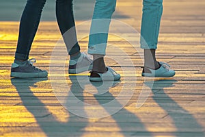 Legs of people walking at sunset. Leisure and recreation in the city