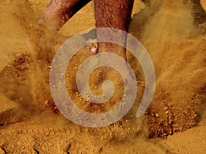 Legs of a person while walking on field ground with thick layer of dirt dust raised