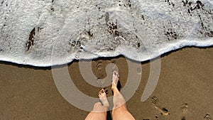 Legs from point of view in front of sea waves on the shore