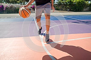 Legs of a professional basketball player dribbling the ball on the basketball field