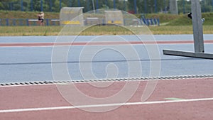 Legs in red snikers of a young woman jog athlete who training running at the city athletics stadium during a day