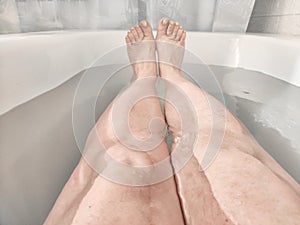 Legs during Relaxing Bath Time in a Tranquil Home Bathroom. Person enjoys a moment of relaxation, with their legs