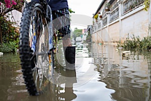 Legs with rubber boots in flooding,Asian man wear waterproof boots with his old bicycle in flooding,after heavy rainfall on the