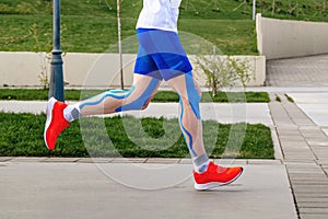 legs runner athlete in blue kinesiotaping on thigh