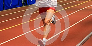 Legs of a runner on an indoor track