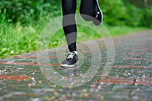 Legs of Running woman atletic spotsman trains in the summer park. Outdoor fitness portrait after rain