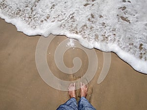 Legs in sand sea water touching feet