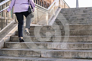 legs of senior woman walking up stairs at city