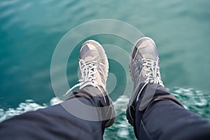 Legs in sneakers on the background of the sea