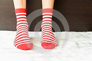 Legs in socks red colors alternate, white side stand on white fabric floor.