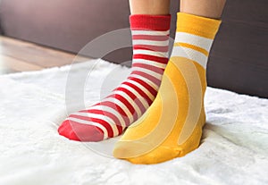 Legs in socks two colors alternate, Red and yellow side stand on white fabric floor.