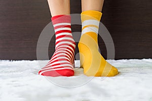Legs in socks two colors alternate, Red and yellow side stand on white fabric floor.