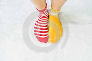 Legs in socks two colors alternate, Red and yellow side stand on white fabric floor.