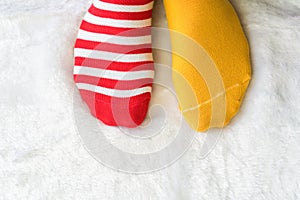 Legs in socks two colors alternate, Red and yellow side stand on white fabric floor.