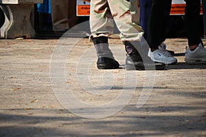 The legs of a soldier wearing military uniform pants and black combat boots stand on the lower left corner of Copy Space.