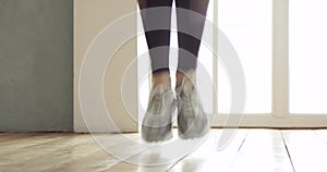 Legs of sporty woman is skipping rope making cardio training at home in kitchen.