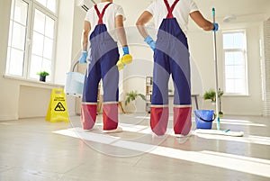 Legs of a team of cleaning service in uniform going to wash the floor with detergent