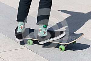 legs of teenager in green socks on a skateboard