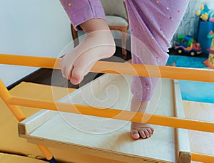 Legs of a todler climbing a frame a staircase of a home sports complex