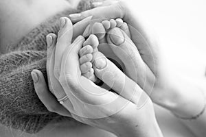 Legs, toes, feet and heels of a newborn. Hands of mother holds the child's legs.
