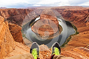 Legs of traveler man sitting on the background of the canyon Horseshoe bend, Arizona, USA. Travel concept, scenic view