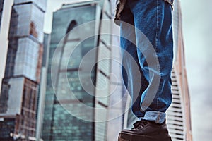 Legs of trendy dressed hipster girl in front of skyscrapers in Moskow city.