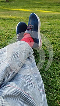 legs in trousers and sneakers on green grass